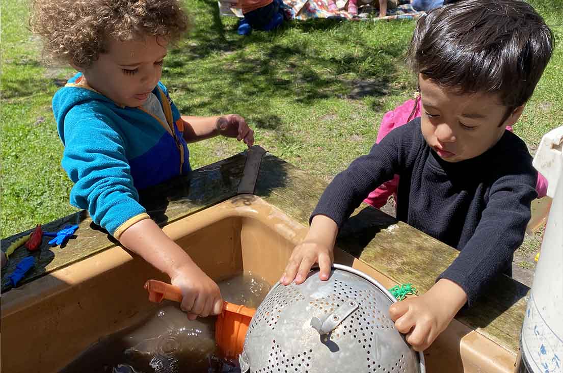 boys playing in water sandbox