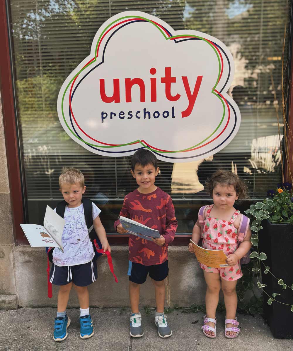 Kids with books on the sidewalk outside of Unity preschool